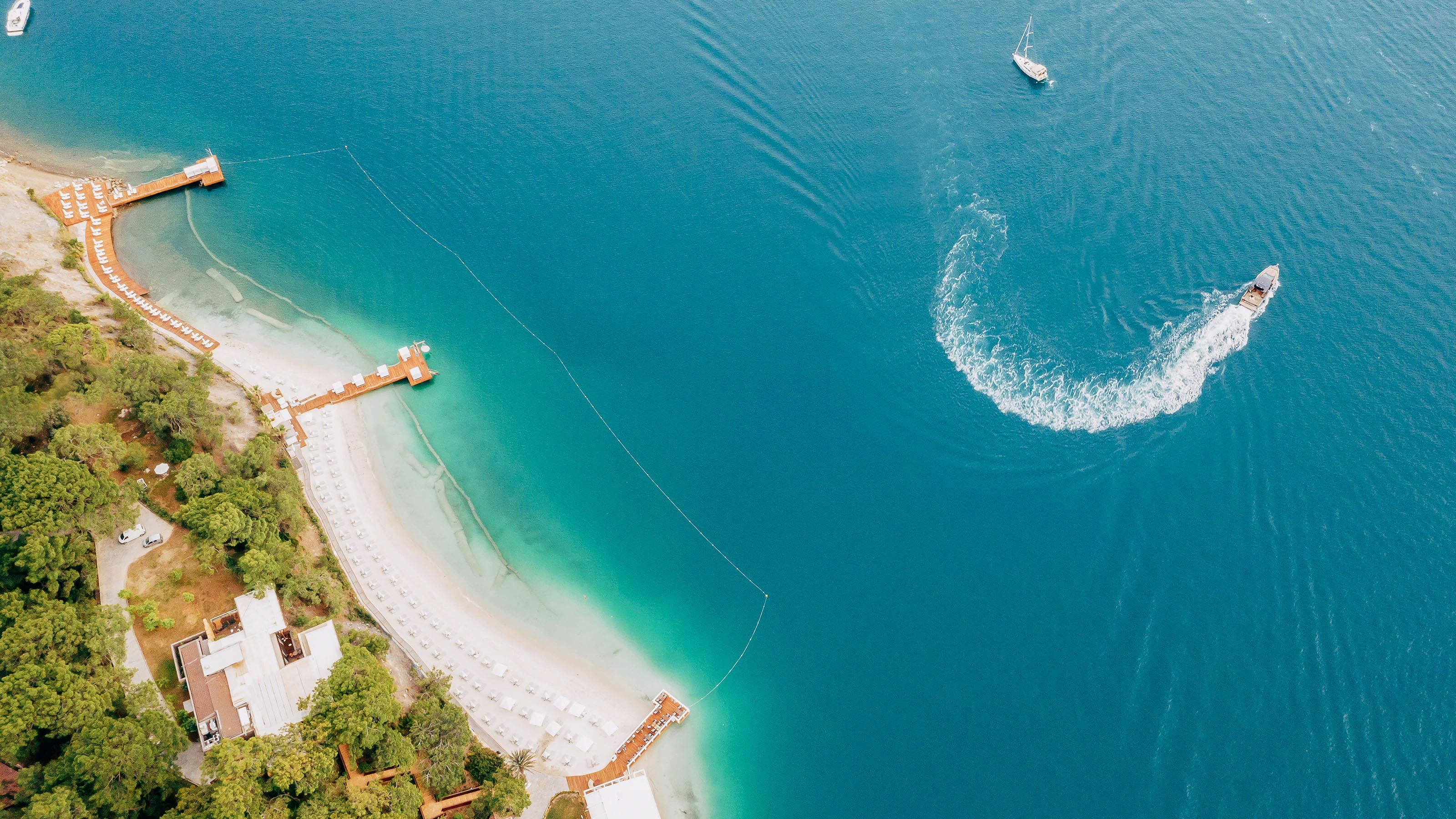 Aerial view of D Resort Gocek private beach with piers, sunbeds and turquoise bay